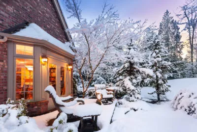 Home blanketed in snow as sun goes down on a winter evening