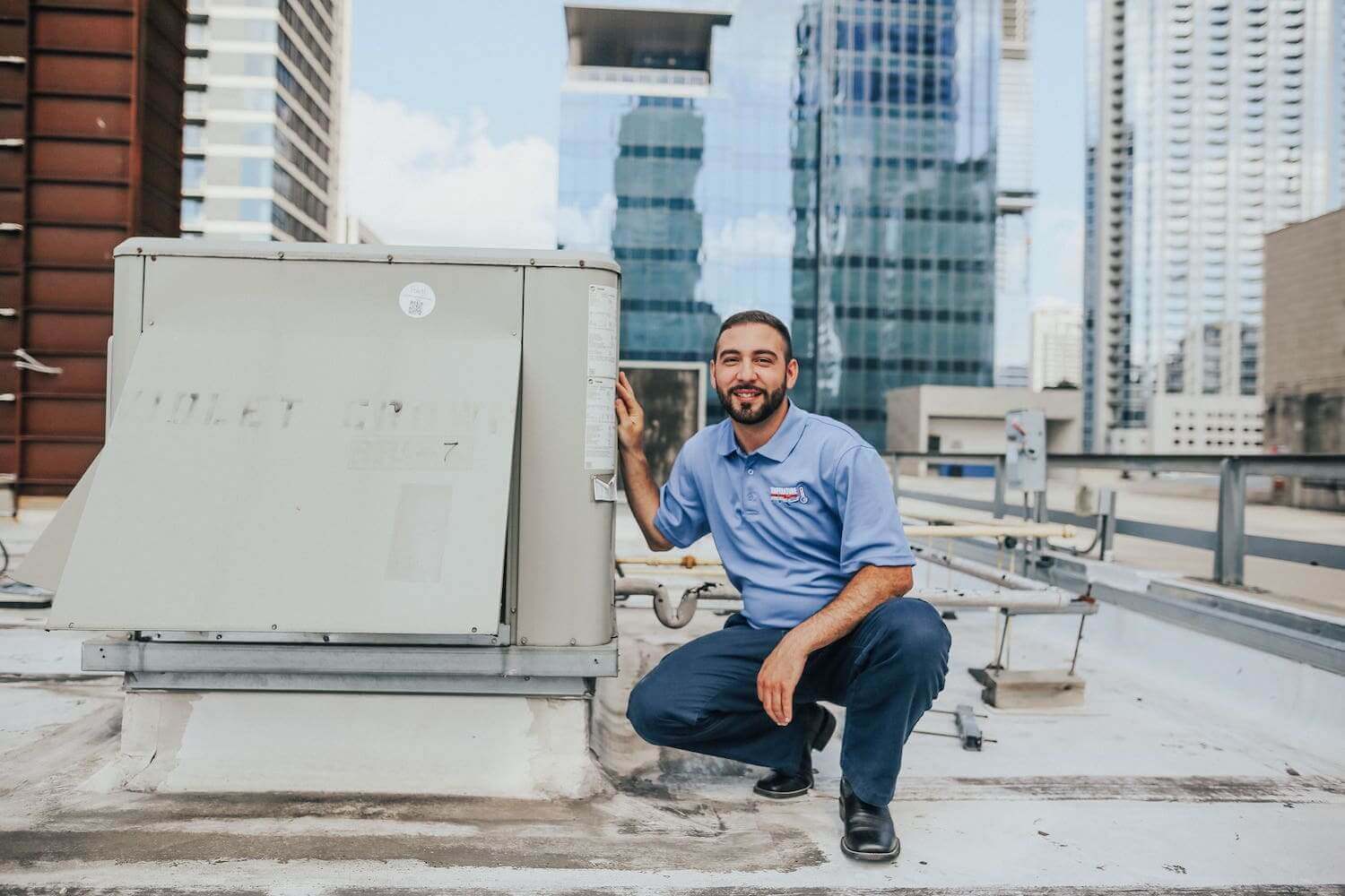 technician smiling next to rooftop unit