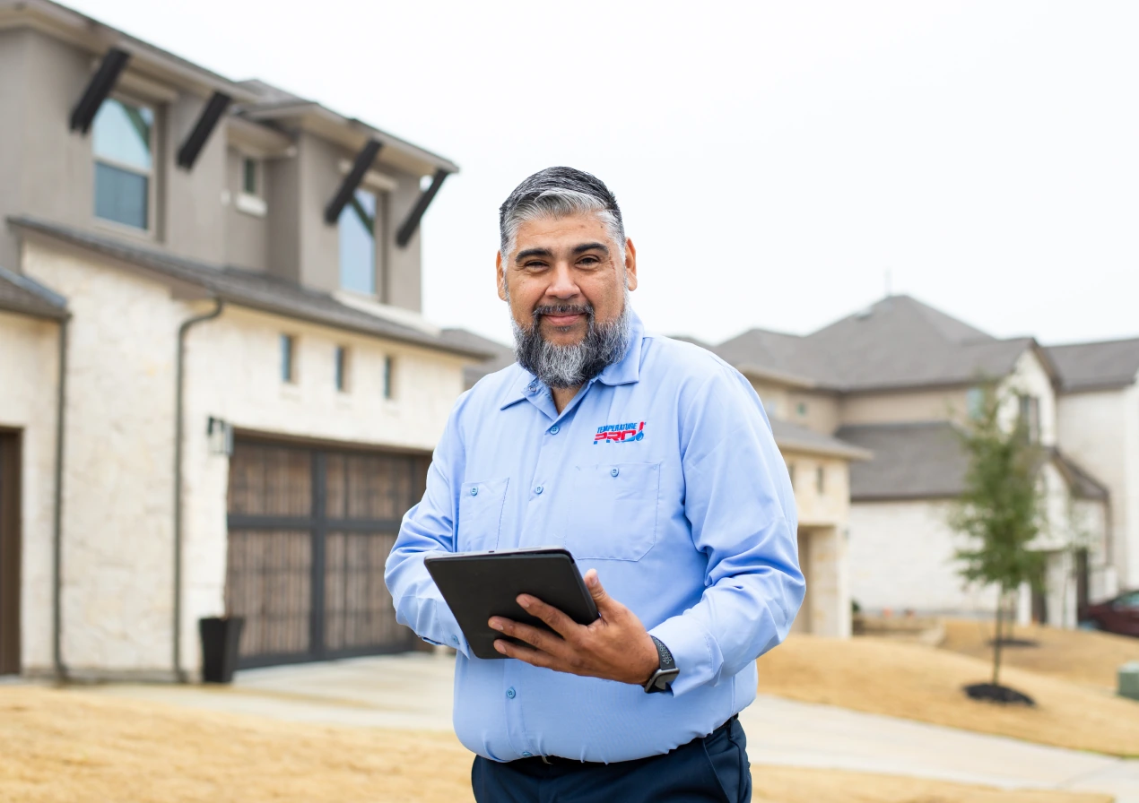 TemperaturePro AC technician standing in front of a customers home, holding an ipad.