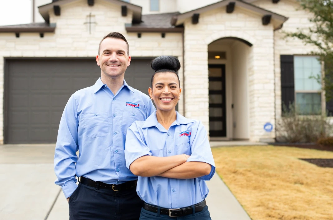 Two AC technicians from TemperaturePro standing in front of a customer’s house after installing an AC unit.