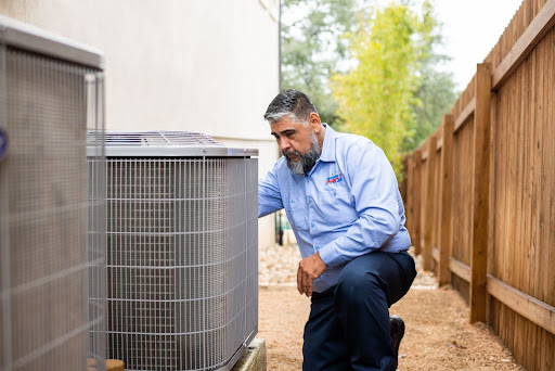 HVAC technician inspecting a broken AC condenser outside of a customer's home.