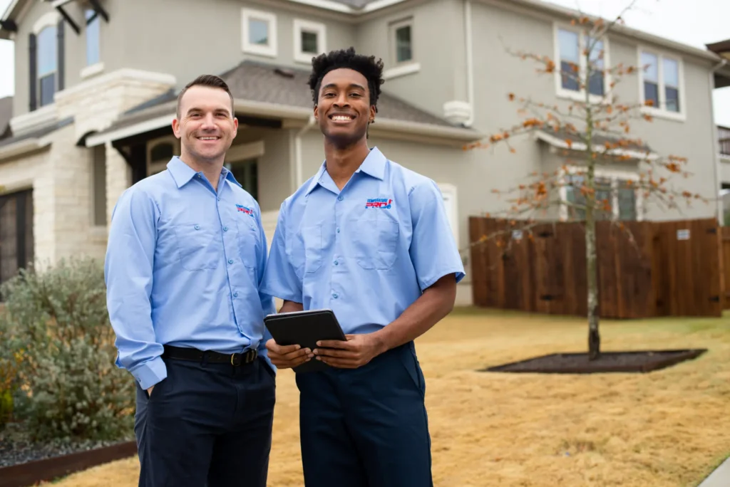 Two TemperaturePro Round Rock heating technicians in front of a home after completing a job.