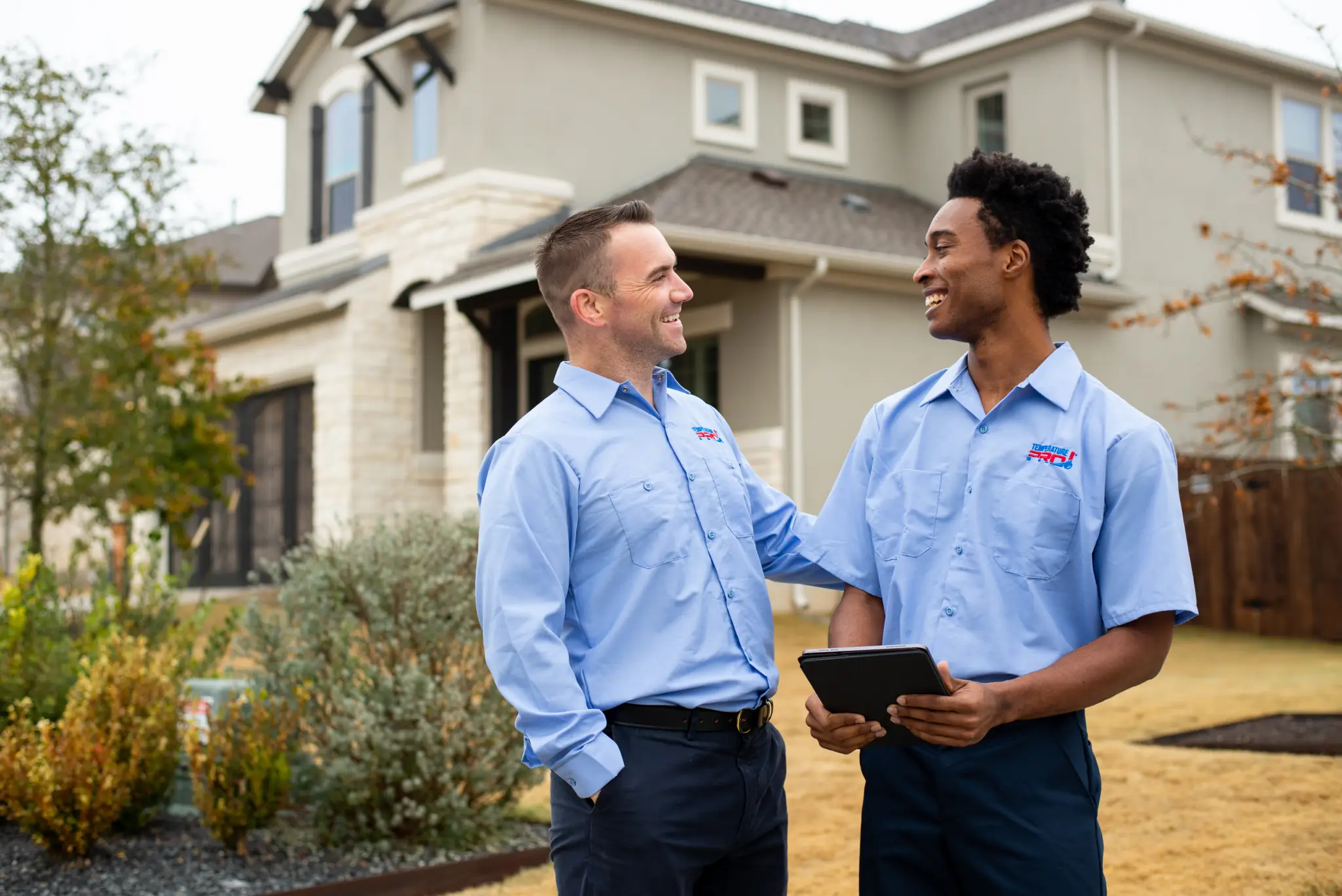 Two TemperaturePro Buxmont heating technicians in front of a home after completing a job.