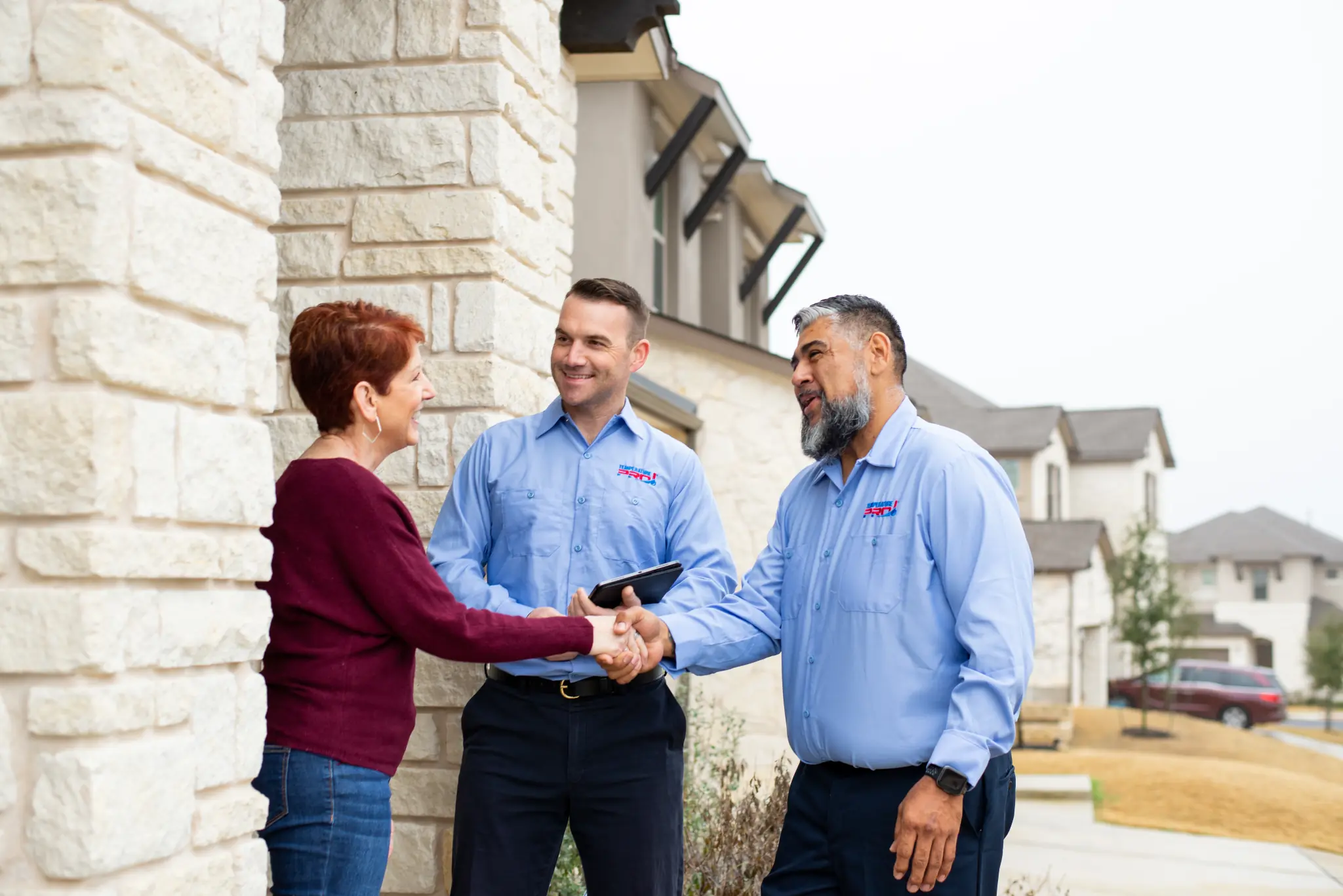 Two Tulsa heating technicians from TemperaturePro shaking a customer's hand after service.