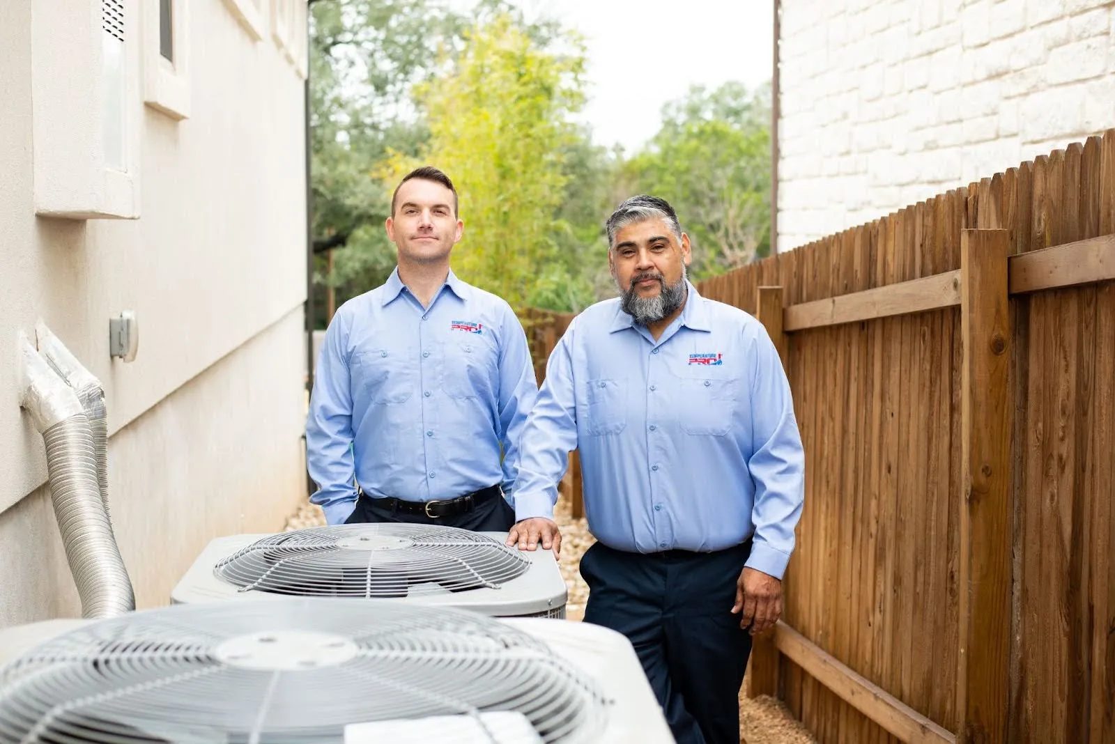Two heating repair technicians in Oklahoma City standing next to a condenser.
