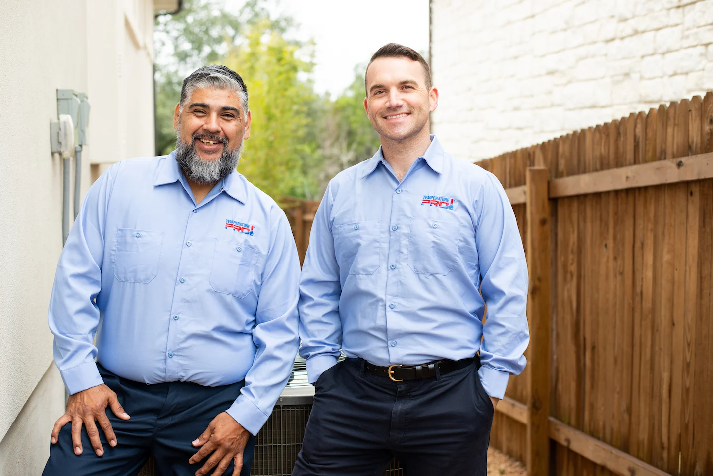 Two furnace repair technicians in Seattle standing next to condensers.