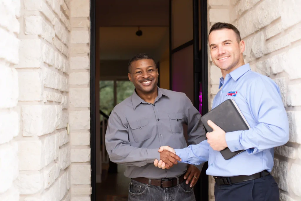 HVAC technician in The Woodlands shaking hands with homeowner in the doorway to the home.