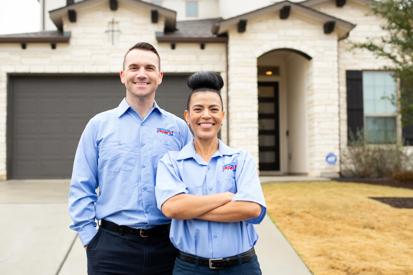 Two AC technicians from TemperaturePro standing in front of a customer’s house.