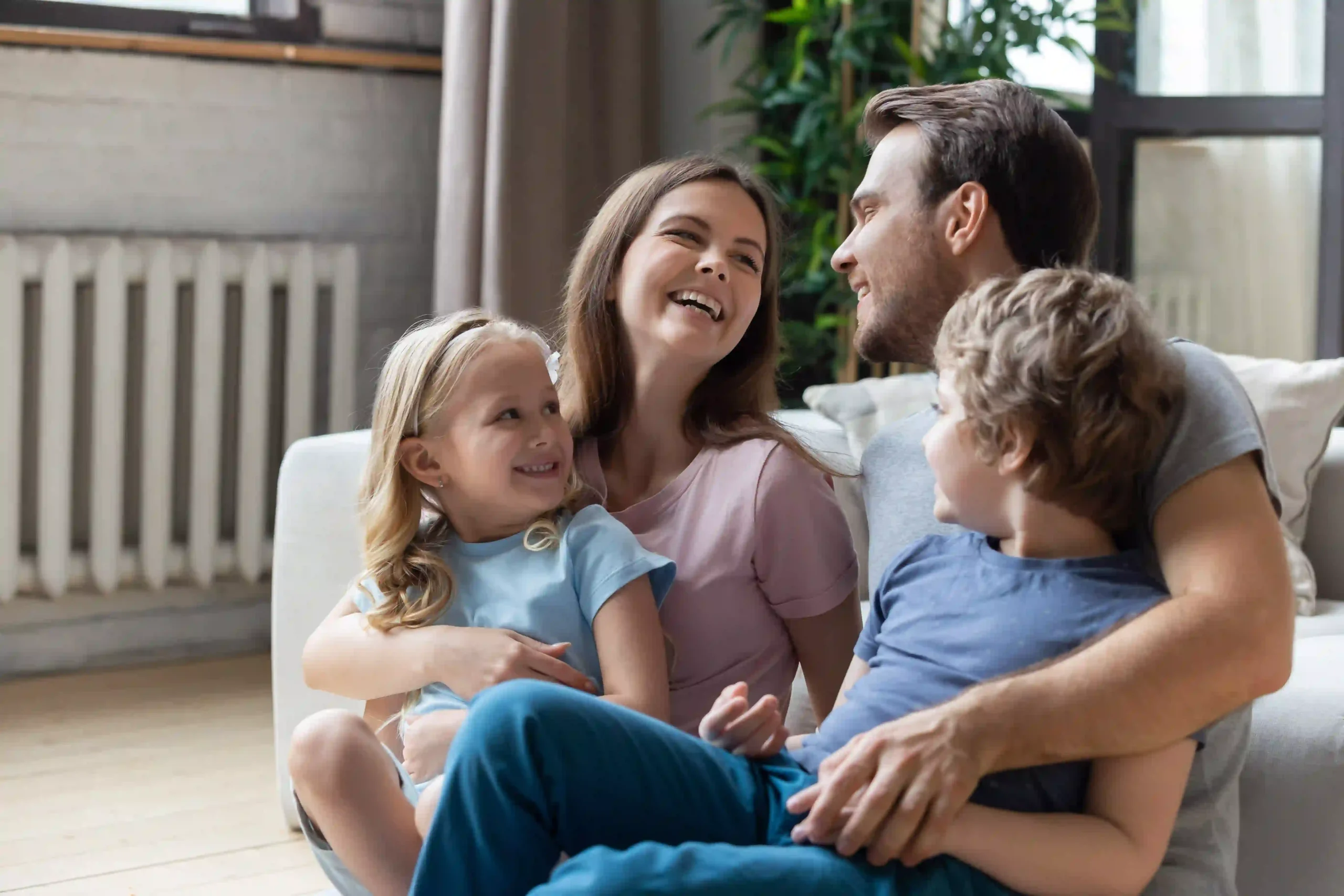 Happy family in Tulsa, Oklahoma sitting on floor next to couch after installing new furnace.