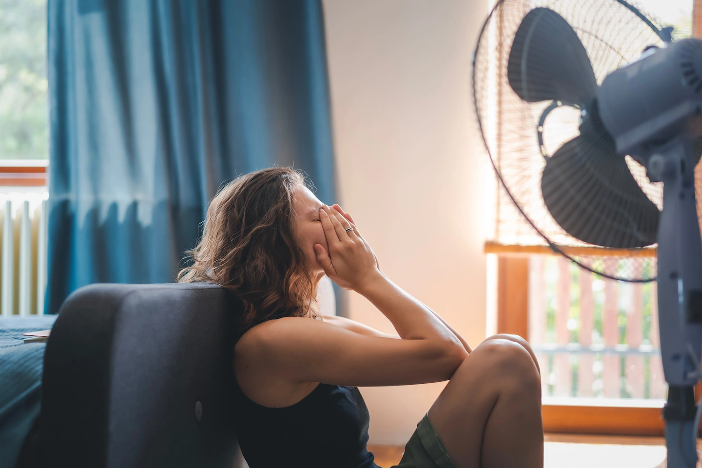 Woman sitting in front of stand up fan in summertime in Conroe because AC not blowing cold air.
