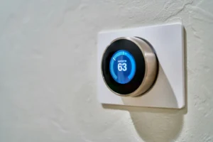 On top of a white baseboard is a digital thermostat that can be turned to change the temperature.