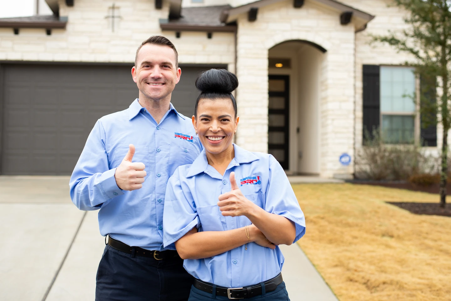 Two TemperaturePro Round Rock HVAC technicians standing next to each other holding thumbs up.