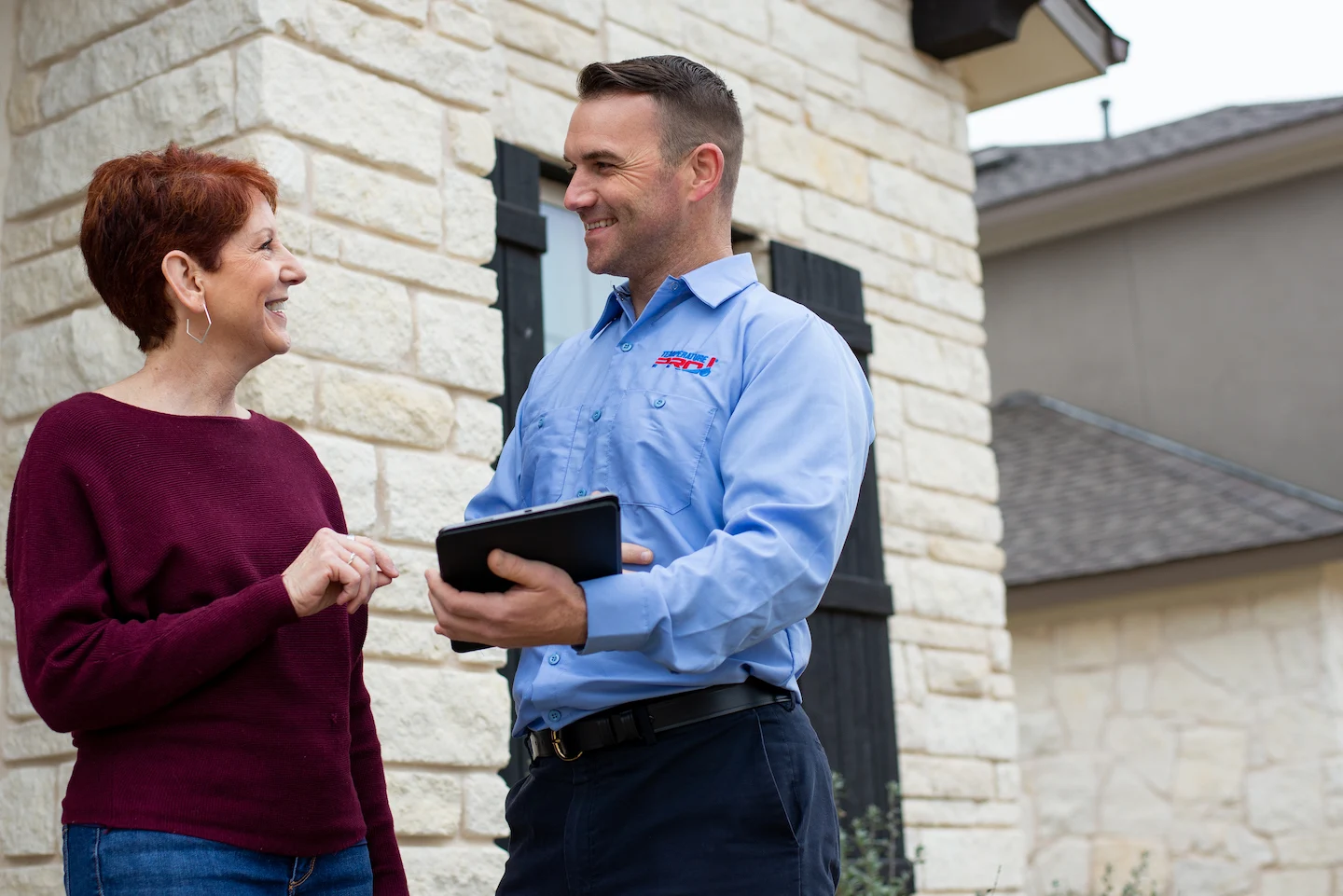 Woman in burgundy sweater talking to duct cleaning technician from TemperaturePro Round Rock.