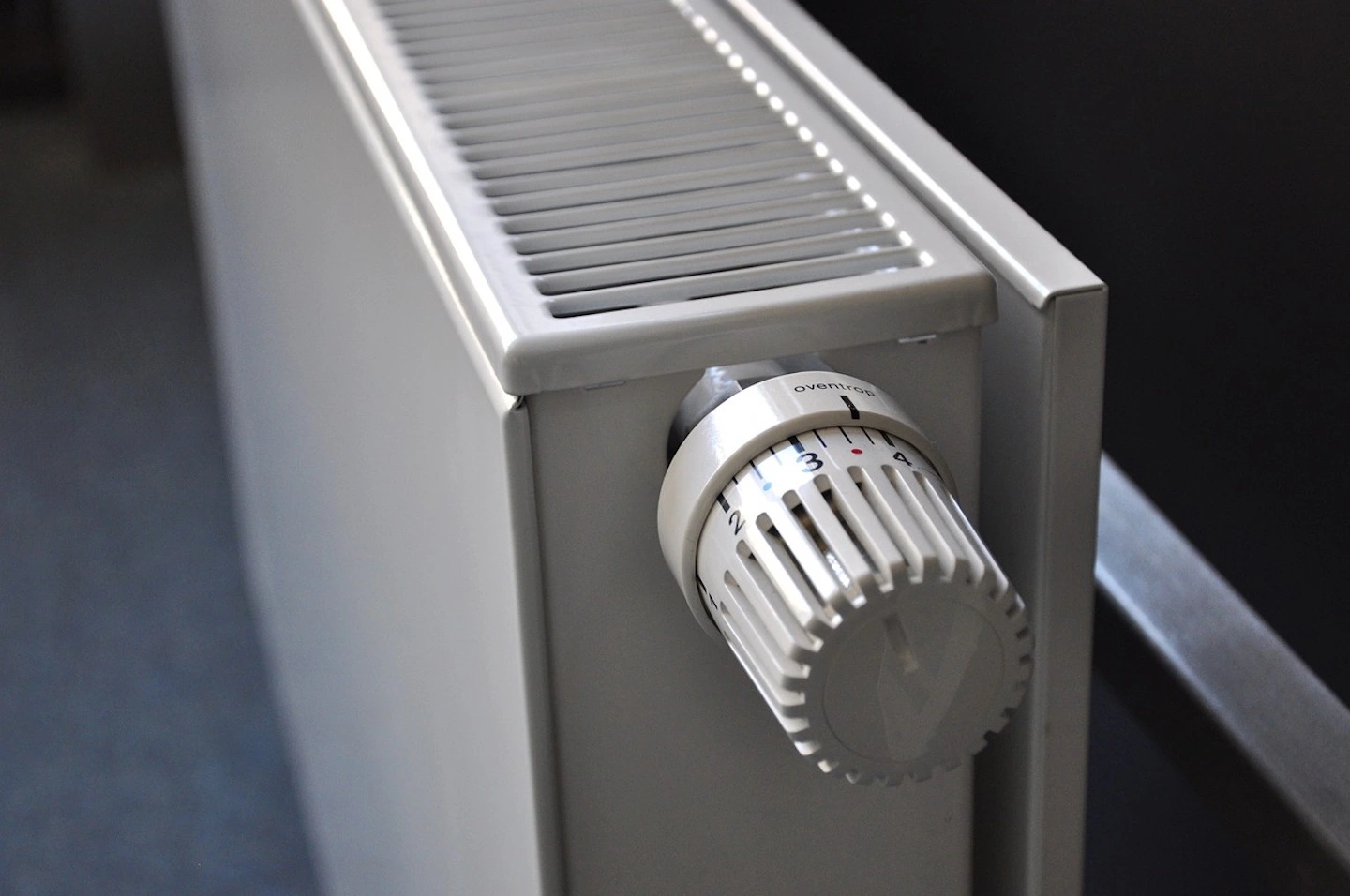 A white radiator with a twistable handle sticking out on the side. 