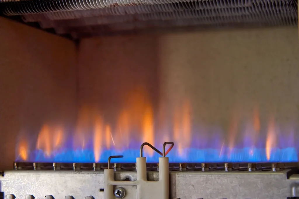 Orange and blue flames coming from a gas furnace in the basement.