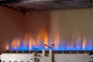 Orange and blue flames coming from a gas furnace in the basement.