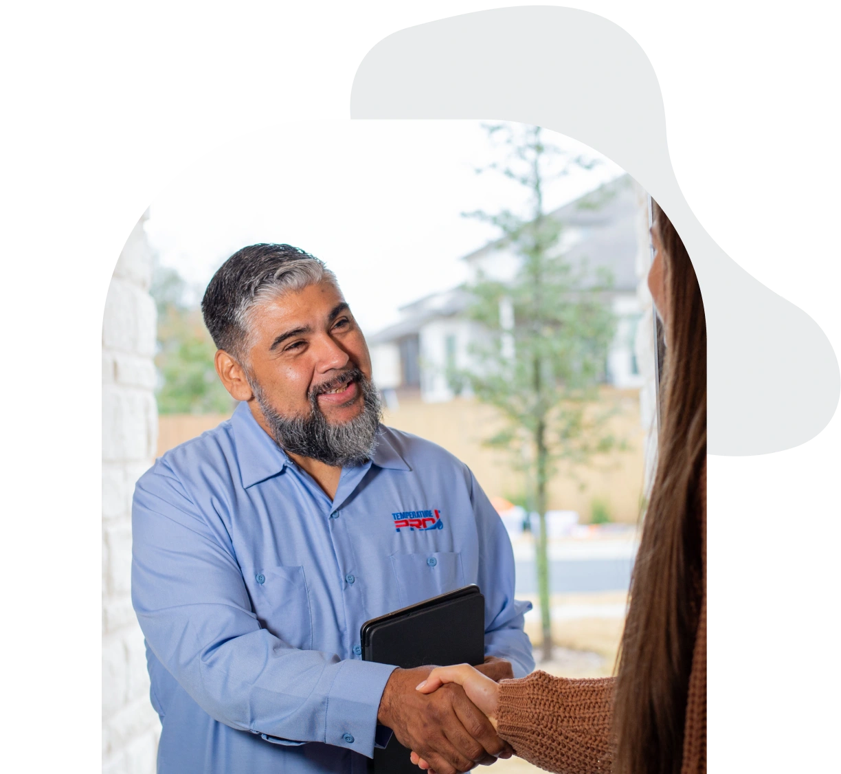 TemperaturePro Conroe Heating technician shaking hands to greet a customer at their front door.