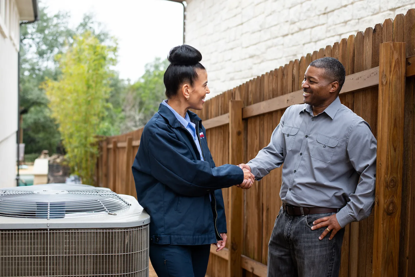 San Jose heating maintenance technician shaking hands with a homeowner outside next to their heat pump.