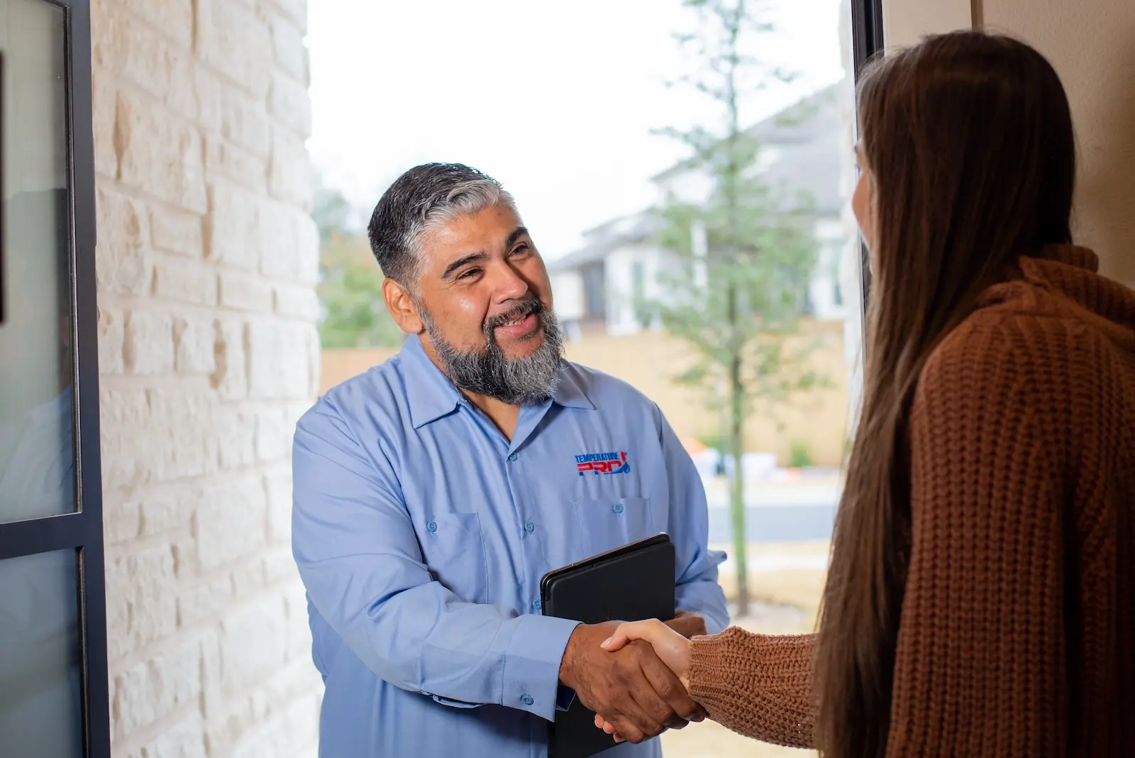 Kirkland heating inspection technician shaking hands with woman in orange sweater.