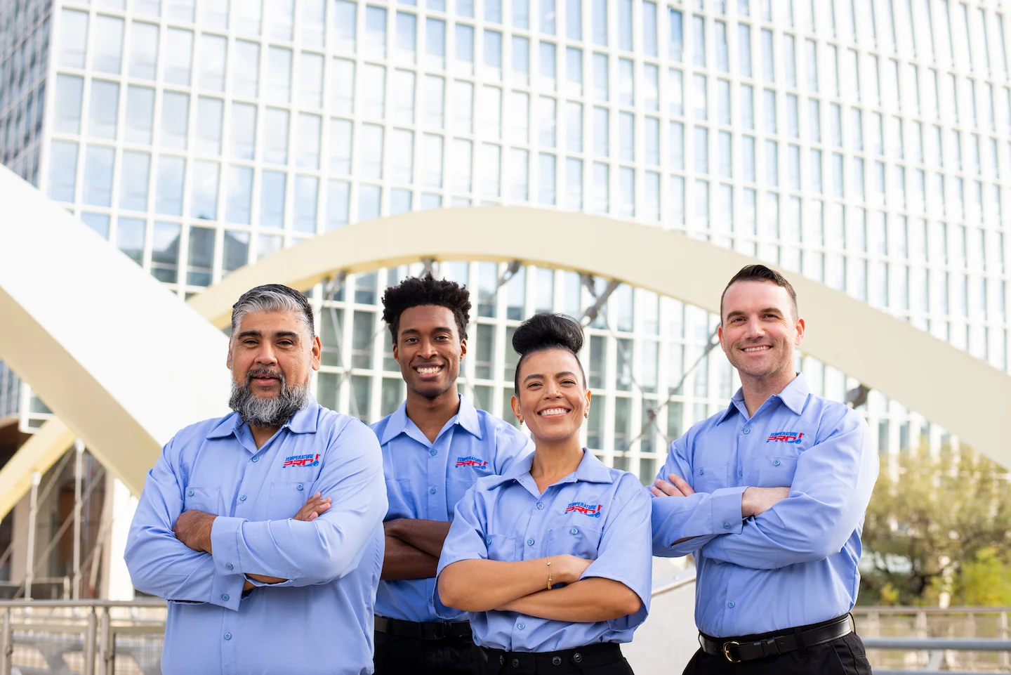 Four AC maintenance technicians from TemperaturePro Round Rock standing in front of a bridge.