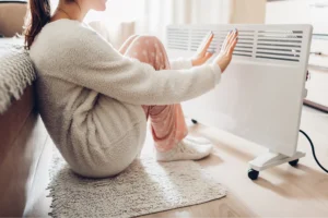 Cold woman warms herself with a heater.