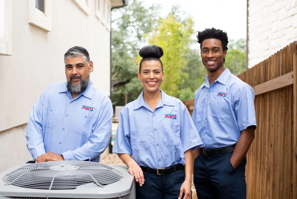 Three TemperaturePro Saskatoon technicians standing next to an AC condenser.