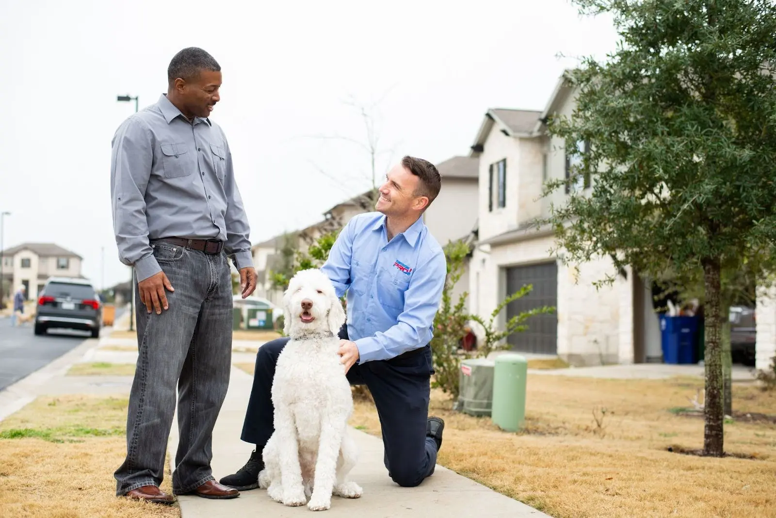 Saskatoon heating repair technician petting dog on the sidewalk outside a home.