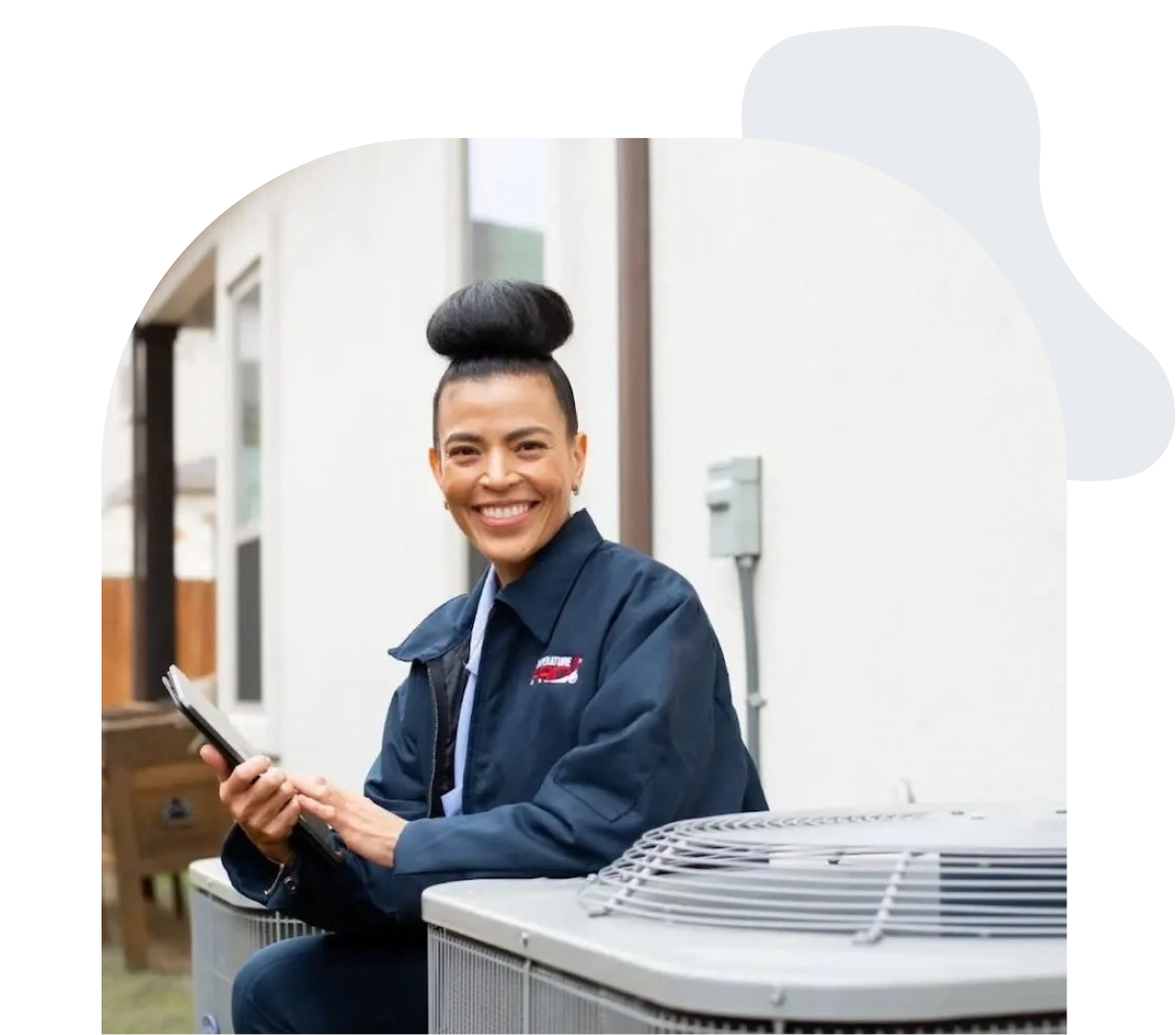 Saskatoon heating technician kneeling next to an HVAC unit outside a customers home.