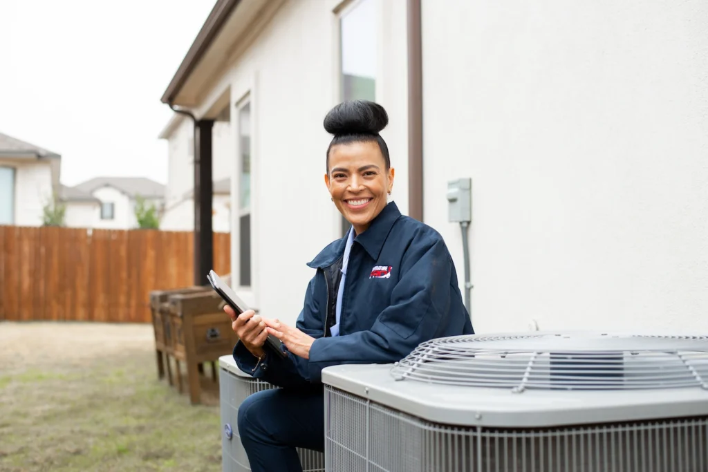 Saskatoon HVAC technician knee;ing next to outdoor heat pump unit.