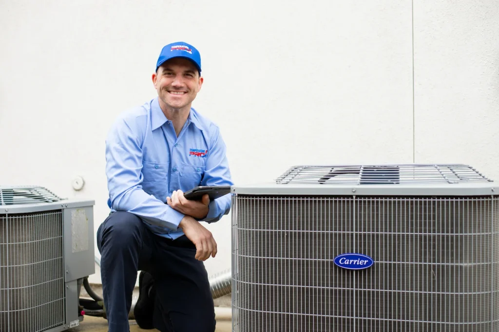 HVAC technician sitting next to AC condenser on side of home in Saskatoon.