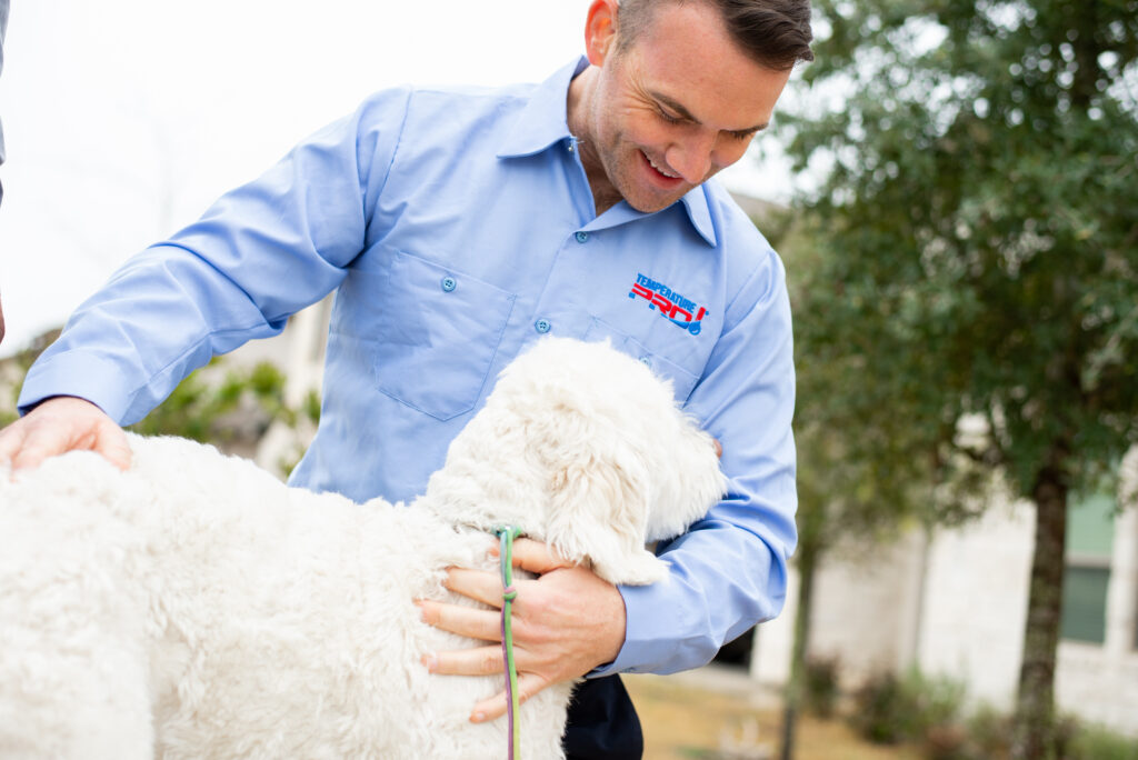 Man pets white labradoodle dog in the front yard of a home in San Jose, CA.