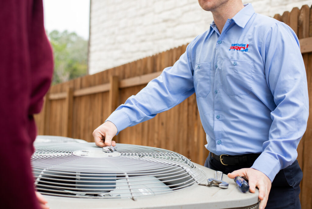 HVAC technician in San Jose inspecting outdoor heat pump unit for repairs.