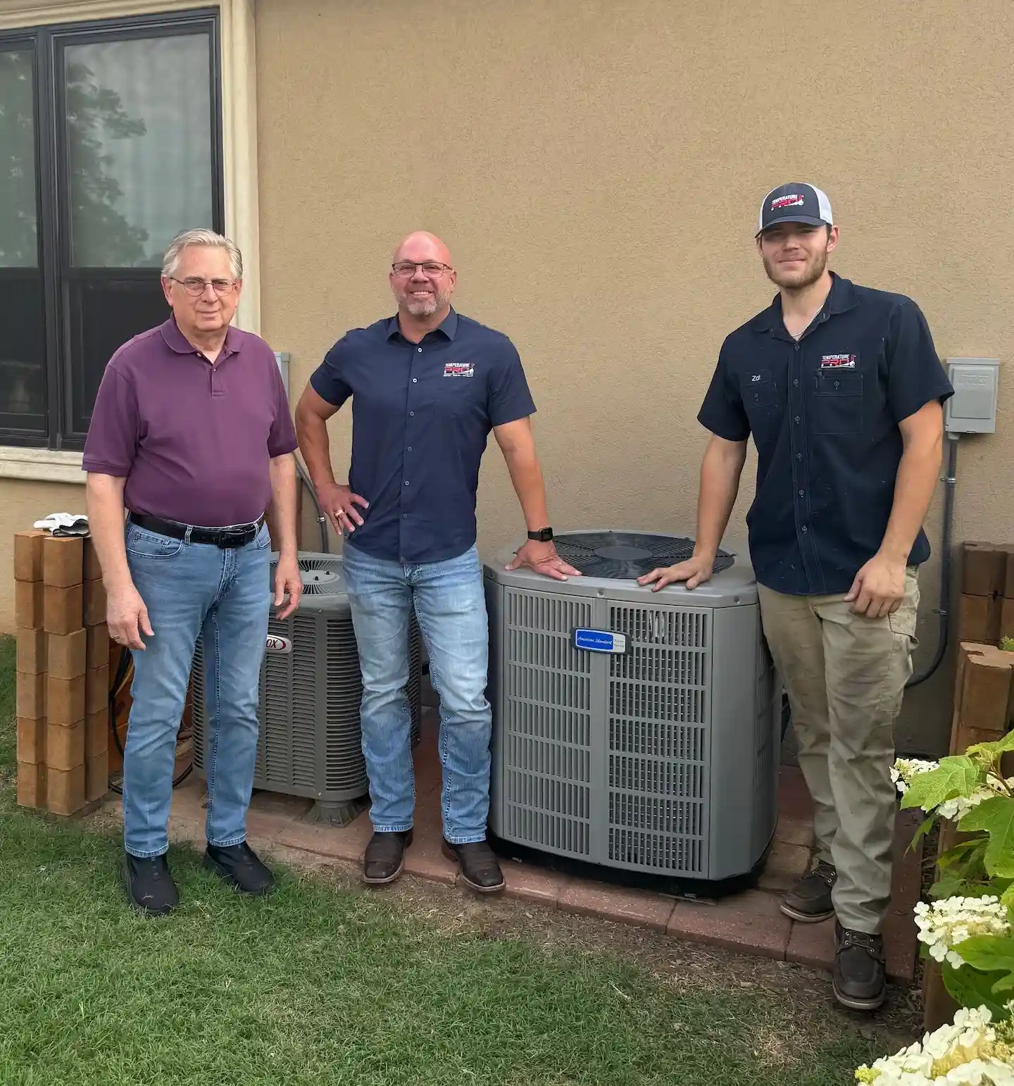 TemperaturePro team standing next to repaired AC system with homeowner.