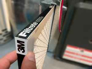 Person inserting a clean filter into their furnace in Saskatoon home.