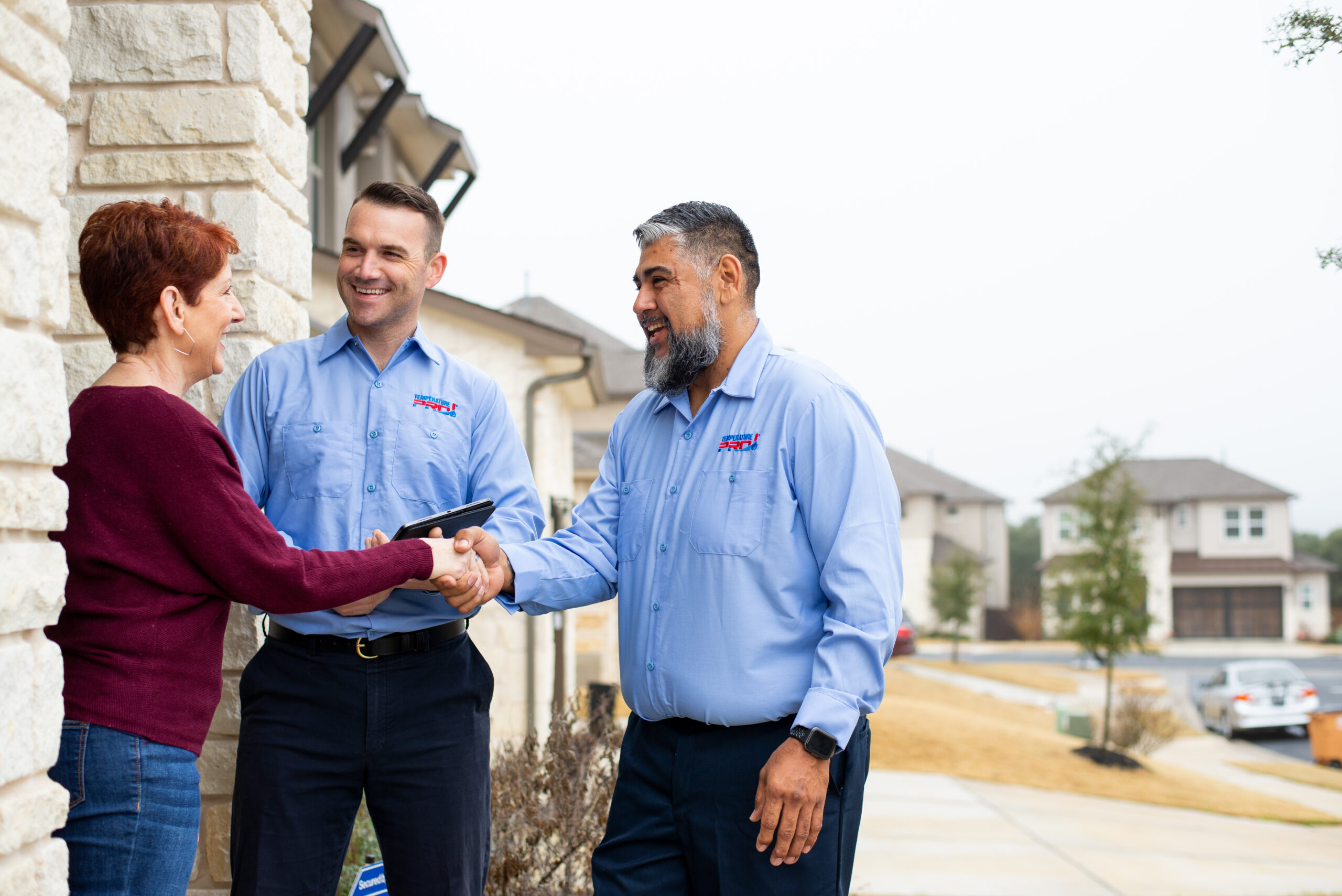 Two TemperaturePro Conroe heating maintenance technicians greeting homeowners at the front door.