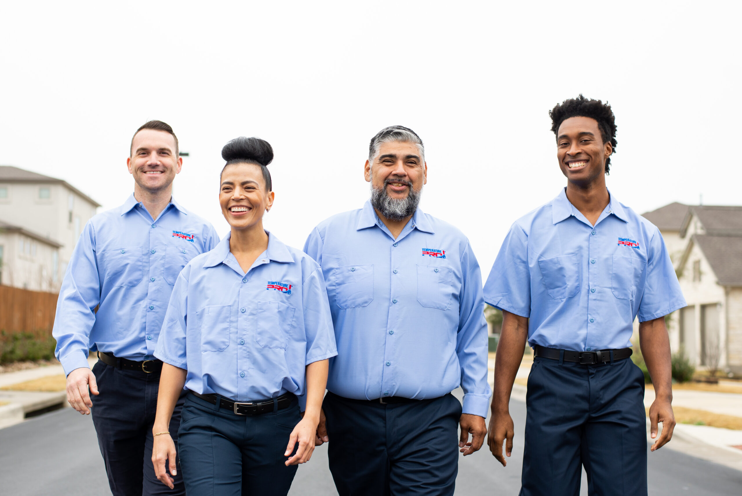 Four TemperaturePro Conroe technicians walking together through a neighborhood street.