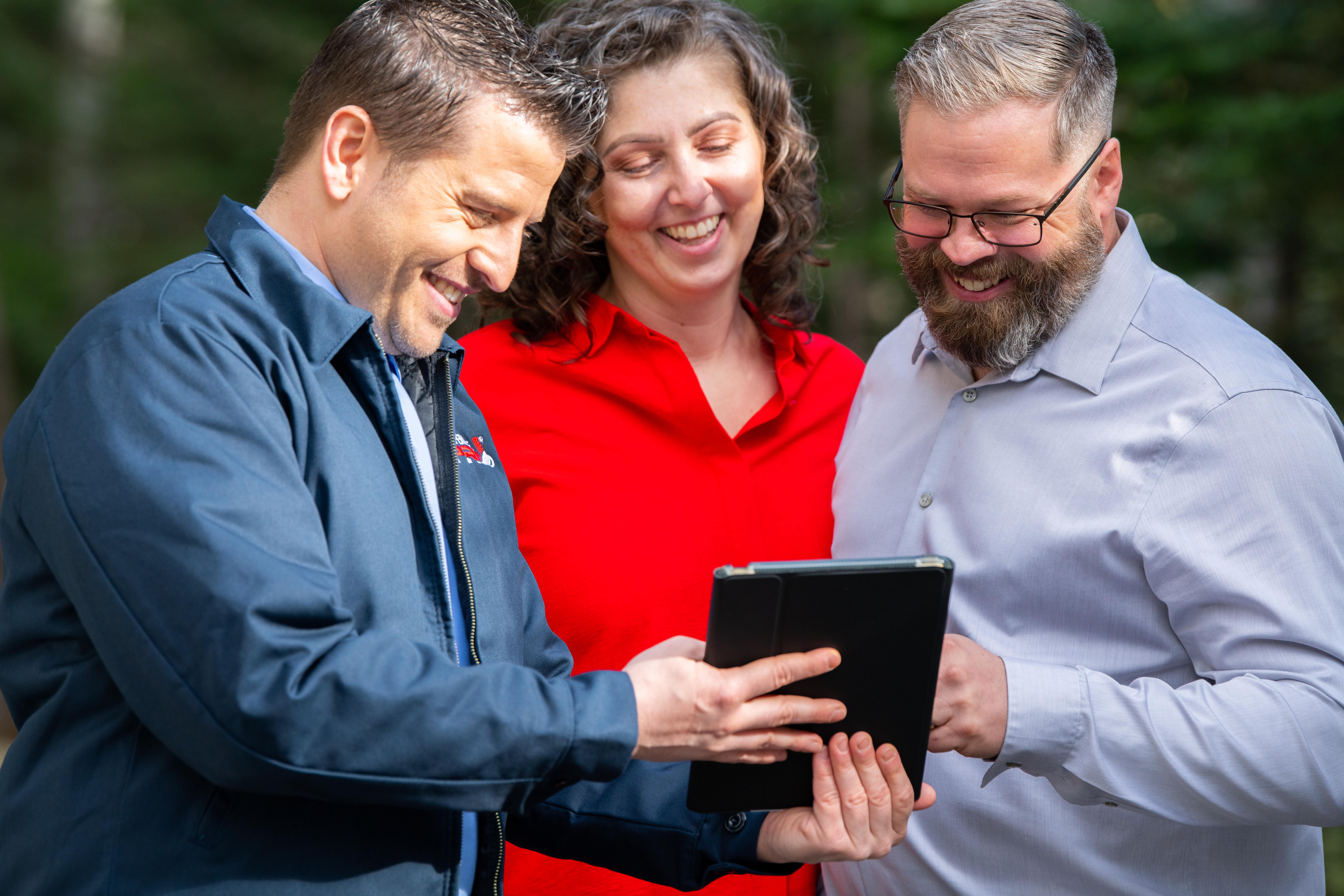 Two homeowners look at an ipad with a TemperaturePro technician to view service details.