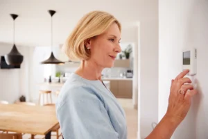 Saskatoon homeowner adjusting a smart thermostat to manage indoor heating during cold winter weather.