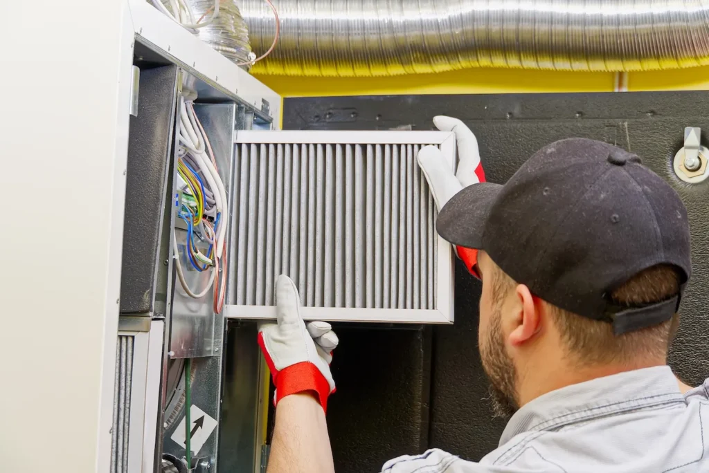 HVAC technician changing out a furnace filter to troubleshoot furnace noises.