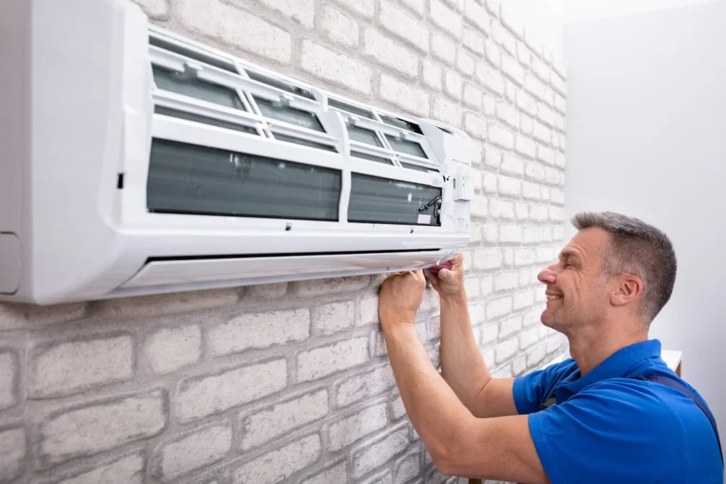 AC technician repairing a wall mounted AC unit