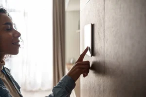 Homeowner adjusting a wall-mounted thermostat inside a home during winter